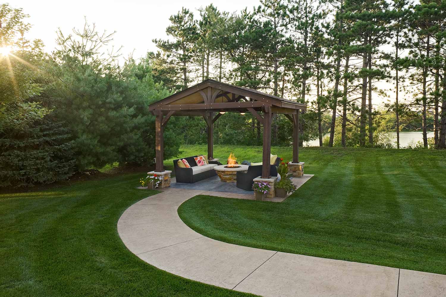 A gazebo with a fire pit in the middle of a lush green field