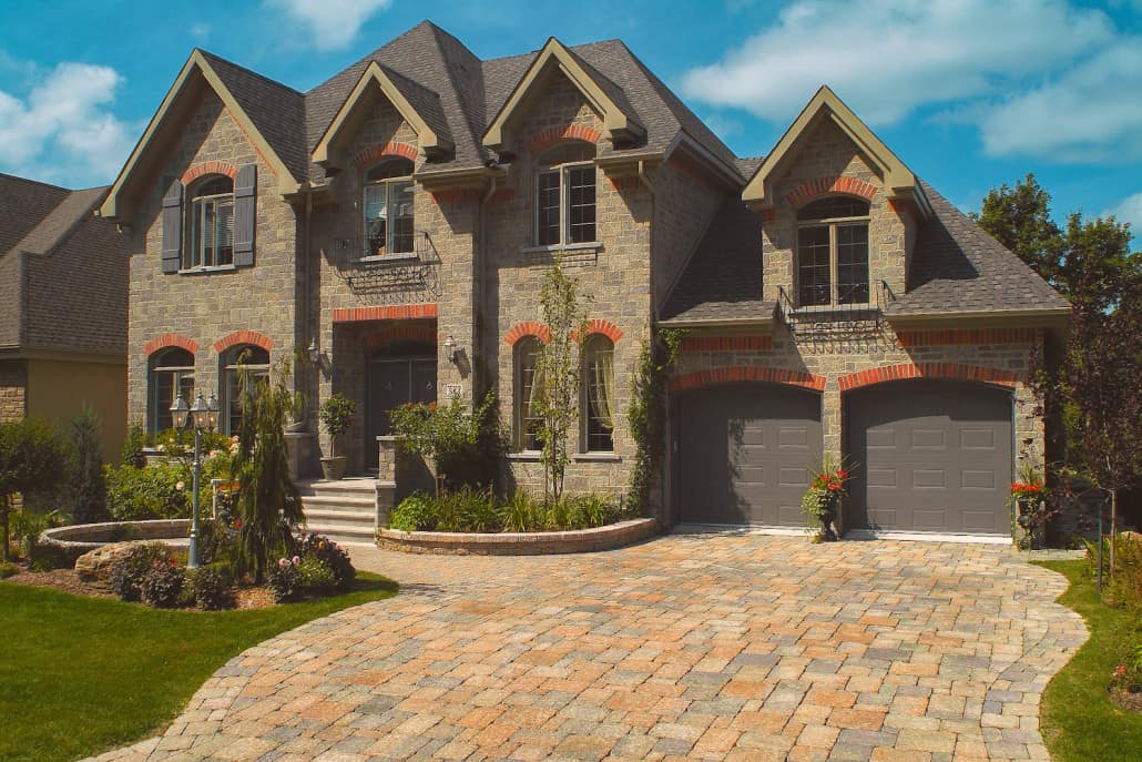 A large house with two garages and a brick driveway