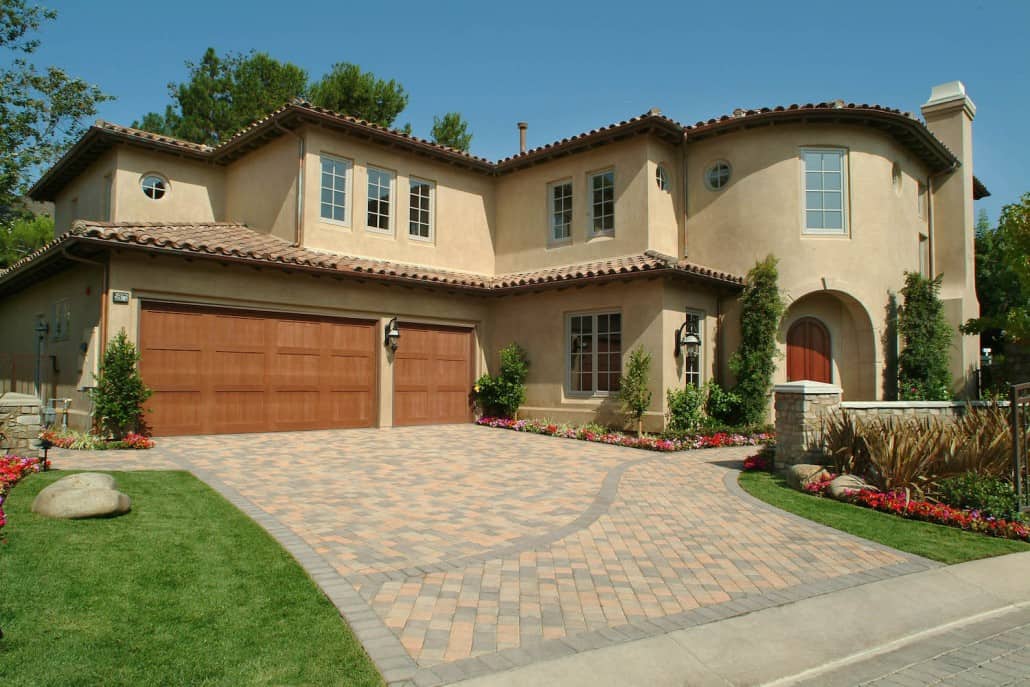 A large house with two garage doors and a brick driveway