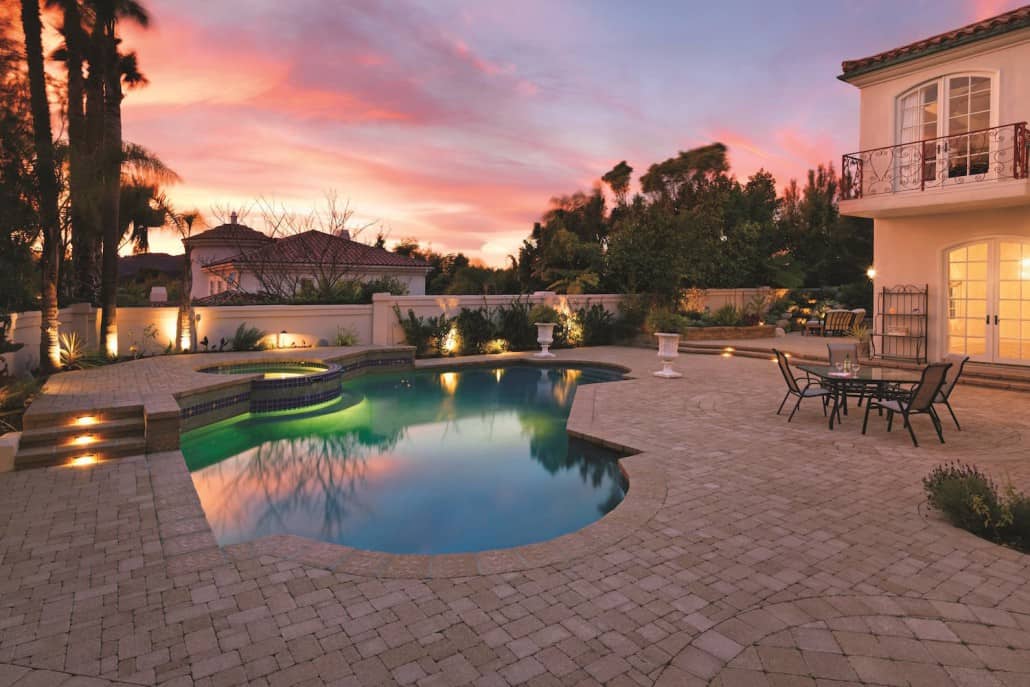 A large swimming pool is in the backyard of a house