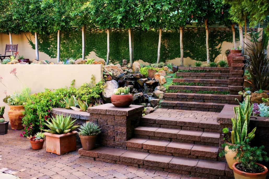 A garden with stairs and potted plants and trees
