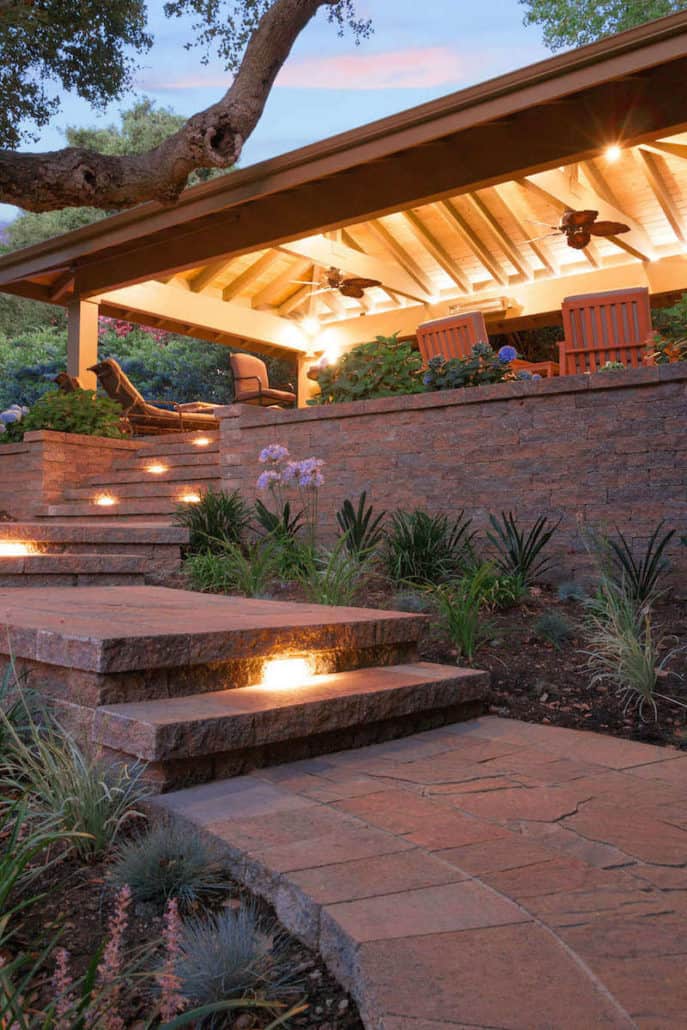 A stone walkway leading to a house with stairs leading up to it.