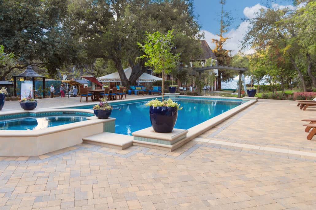 A large swimming pool with a hot tub in the middle of it