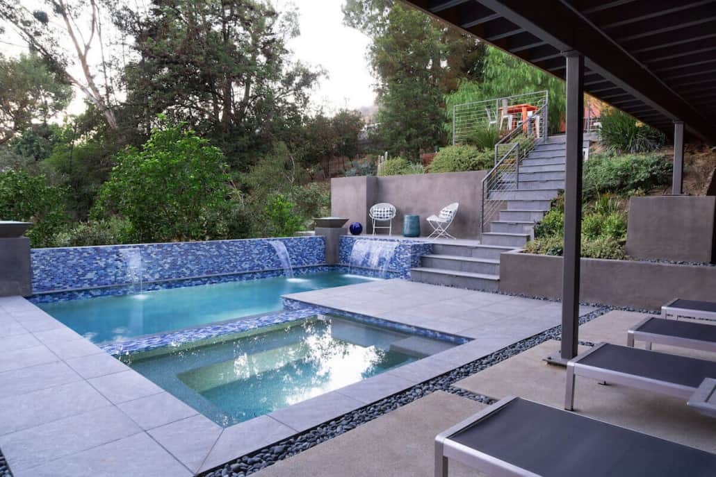 A large swimming pool with a hot tub underneath it