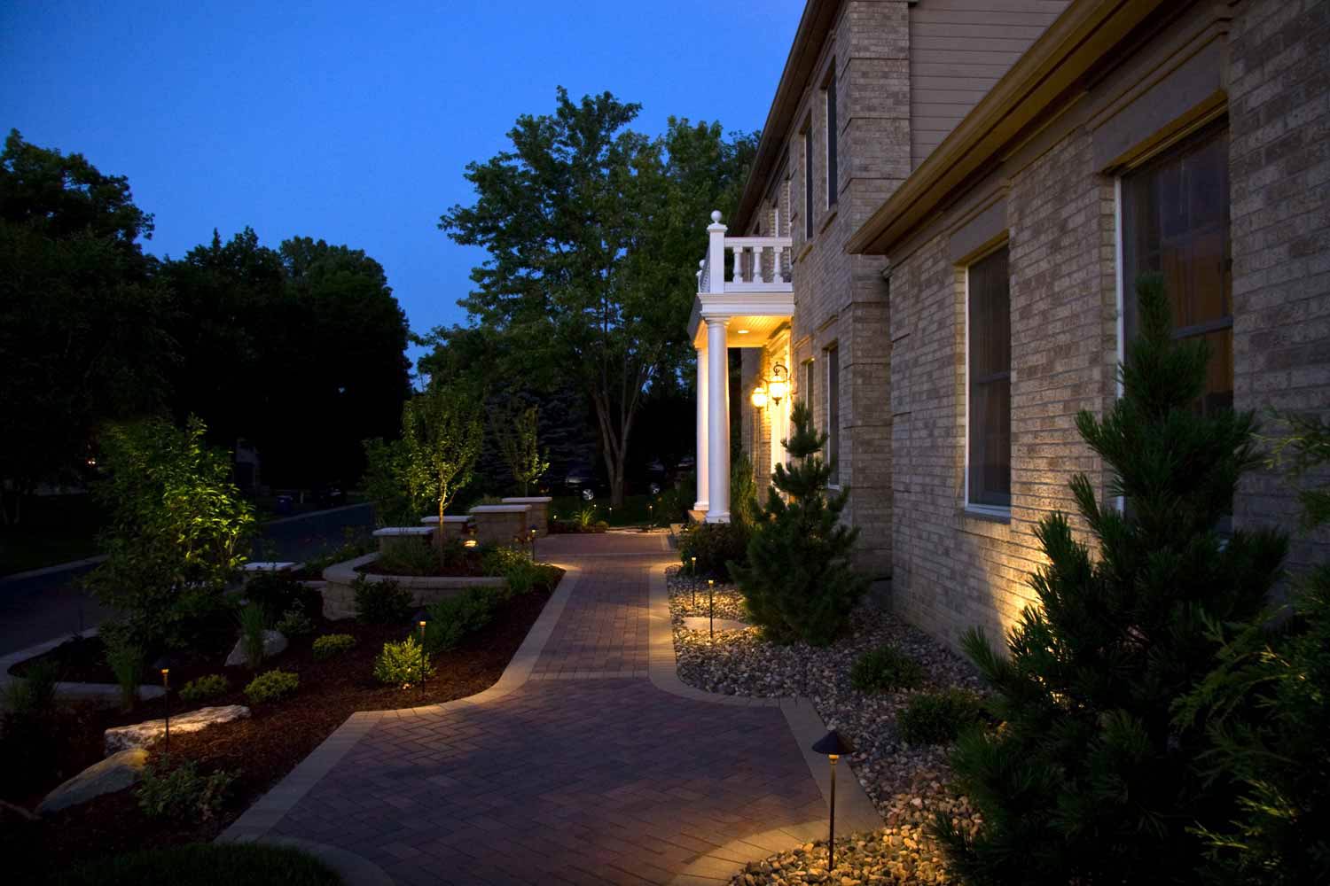 A brick house with a walkway leading to the front door at night.