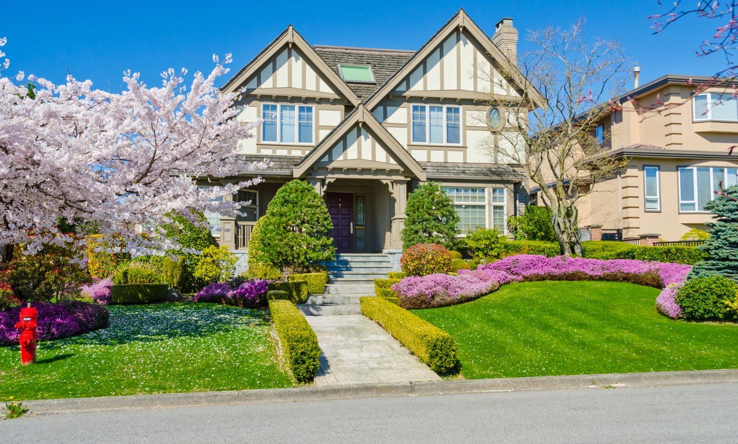 A large house with a lush green lawn and flowers in front of it.