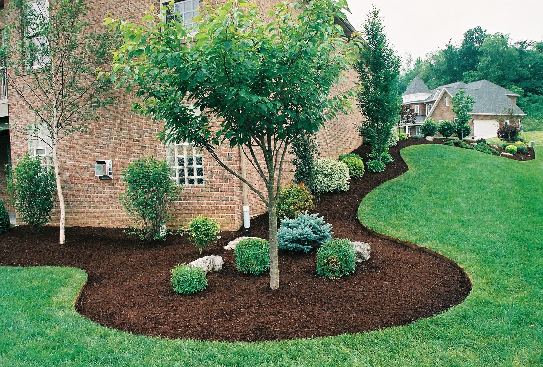 A brick house with a lush green lawn in front of it