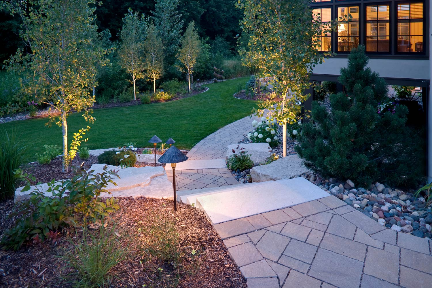 A patio with lights on it and a house in the background at night.