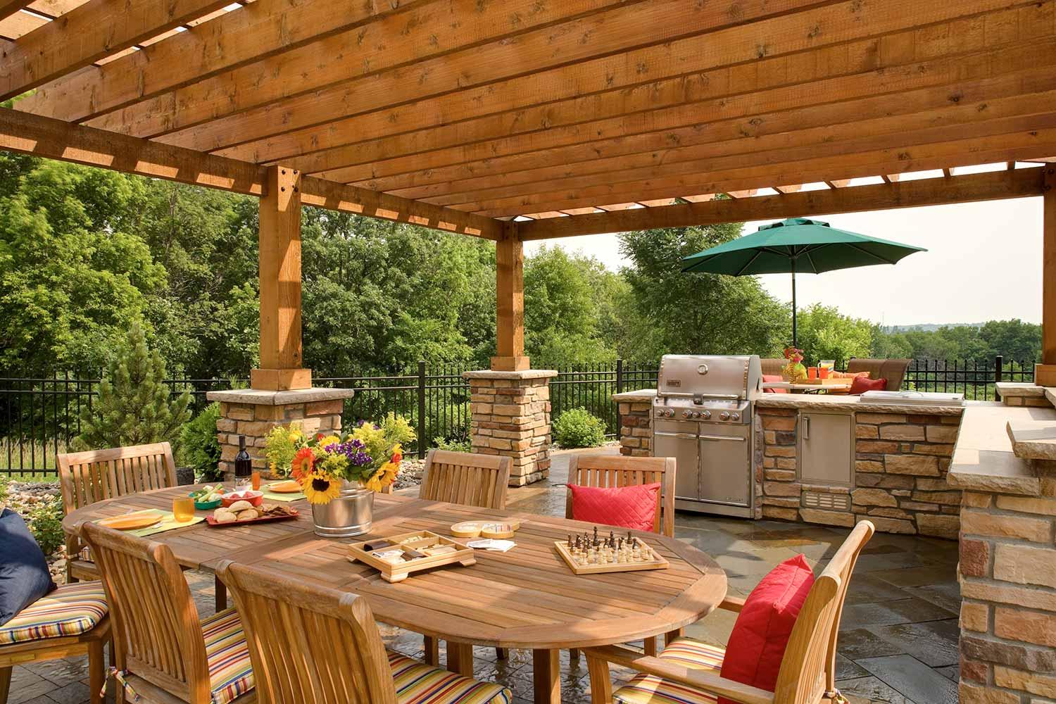 A patio with a table and chairs under a wooden pergola.