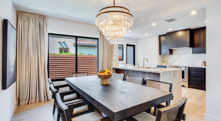 A dining room with a table and chairs and a chandelier hanging from the ceiling.