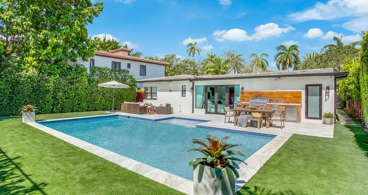 A large swimming pool is in the backyard of a house.