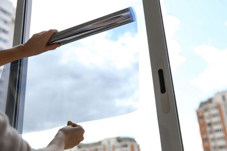 A person is applying window tinting to a window.