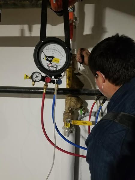 A man is working on a pipe with a gauge on it