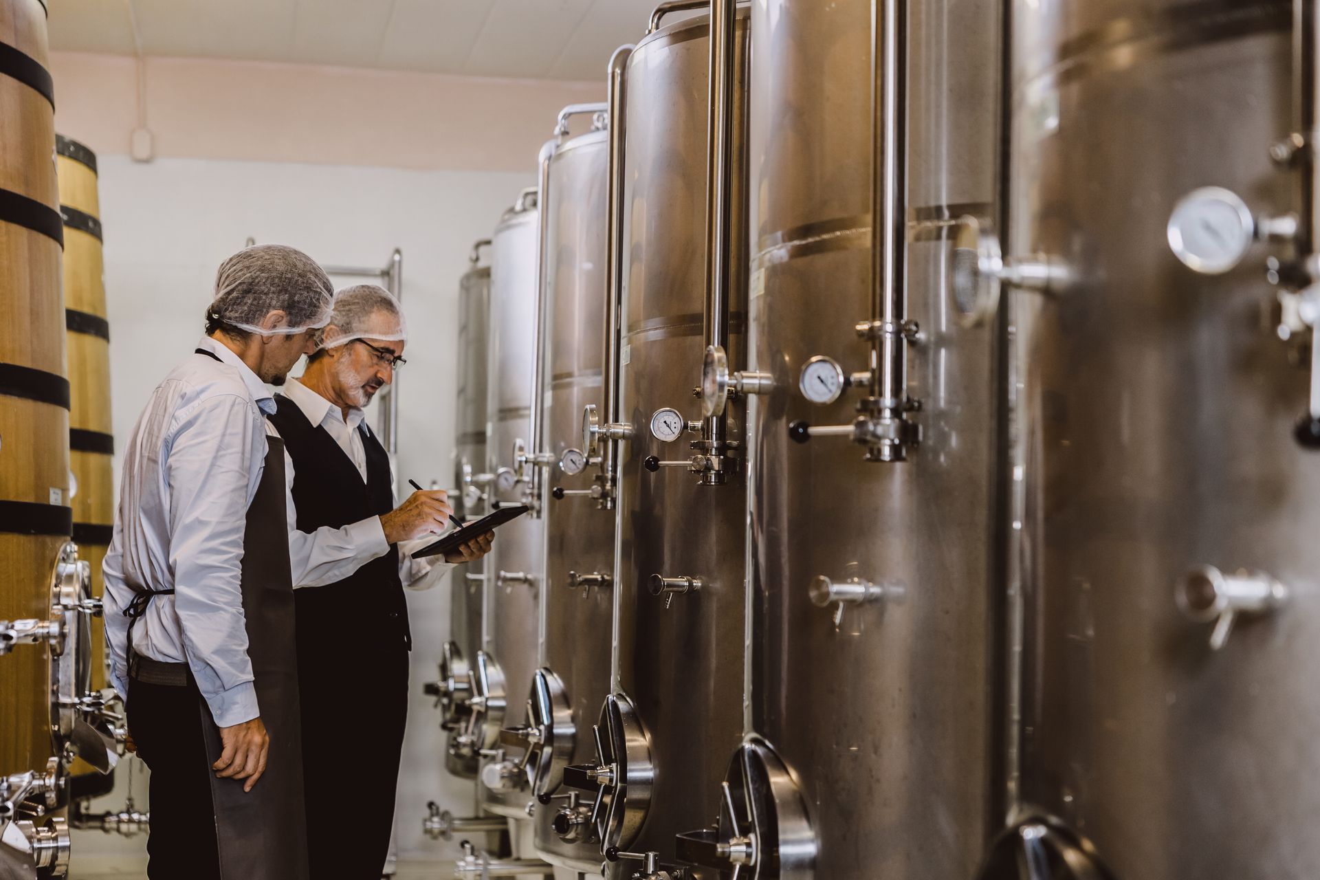 Two men are standing in a factory looking at a clipboard.