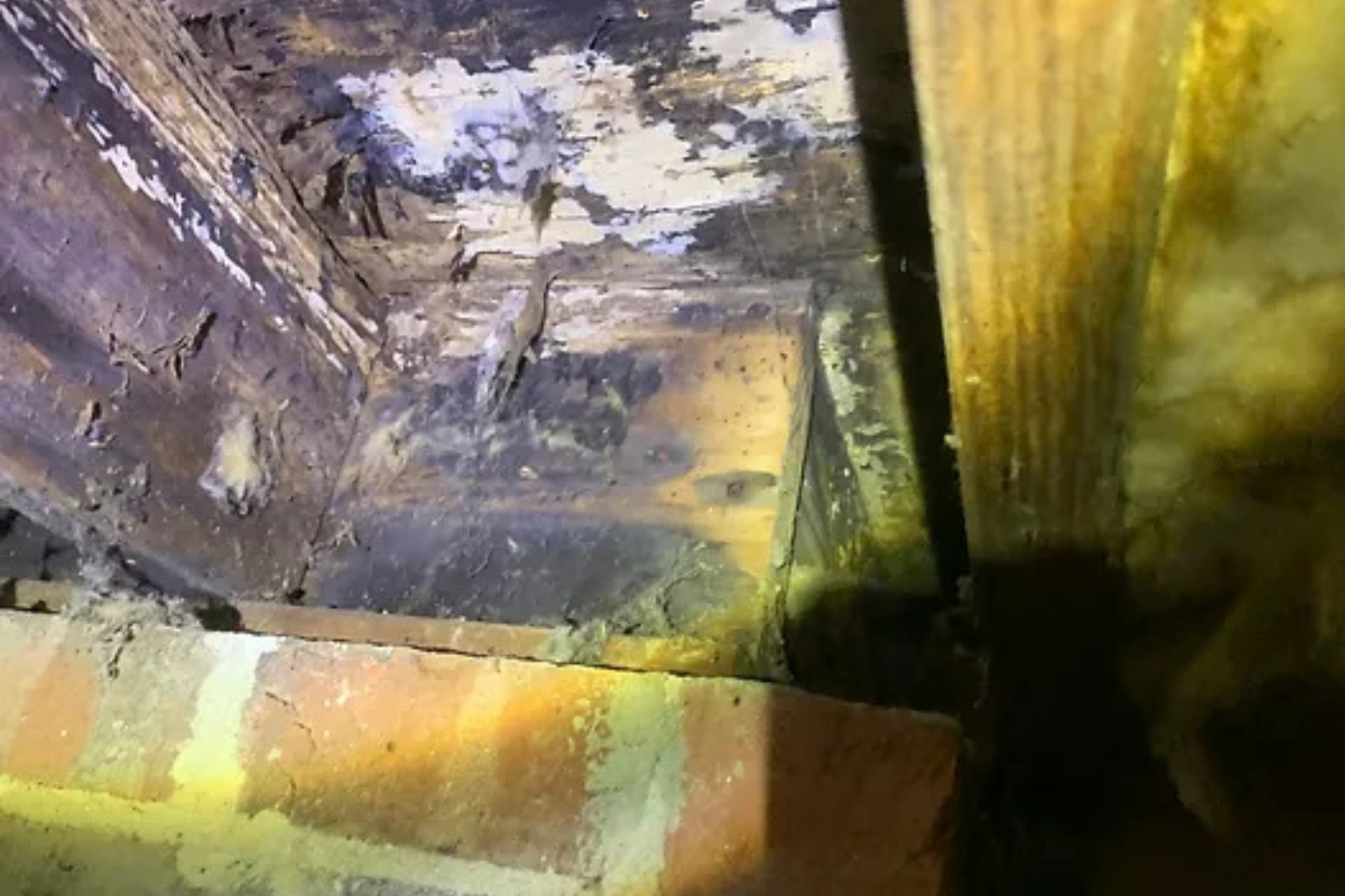 A close up of a piece of wood in a room with a brick wall.