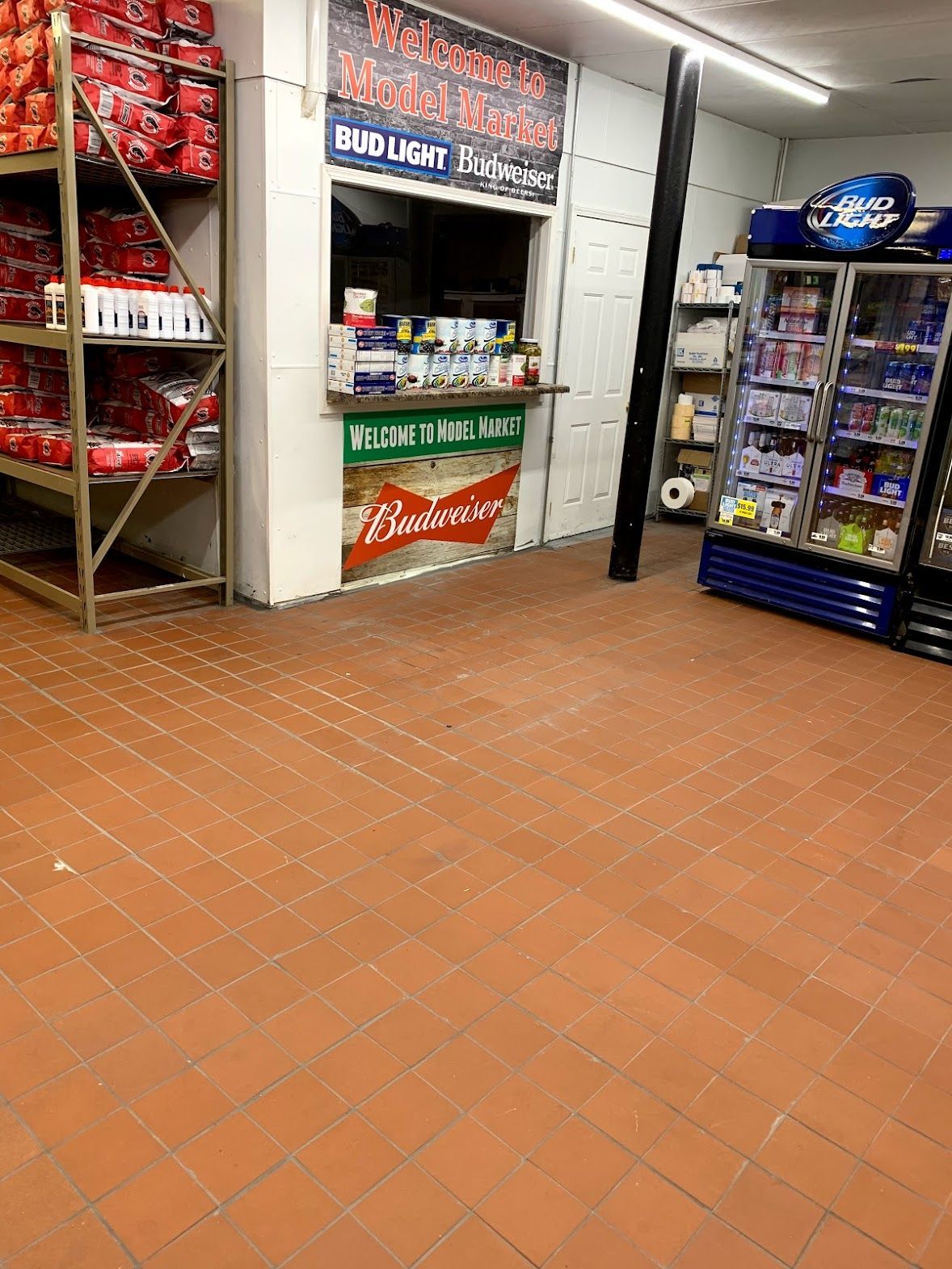 A convenience store interior with shelves of products, a counter, and a drink cooler.