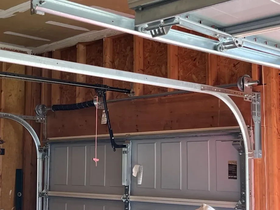 Garage door opening, with metal tracks, wood paneling, and visible opener components.