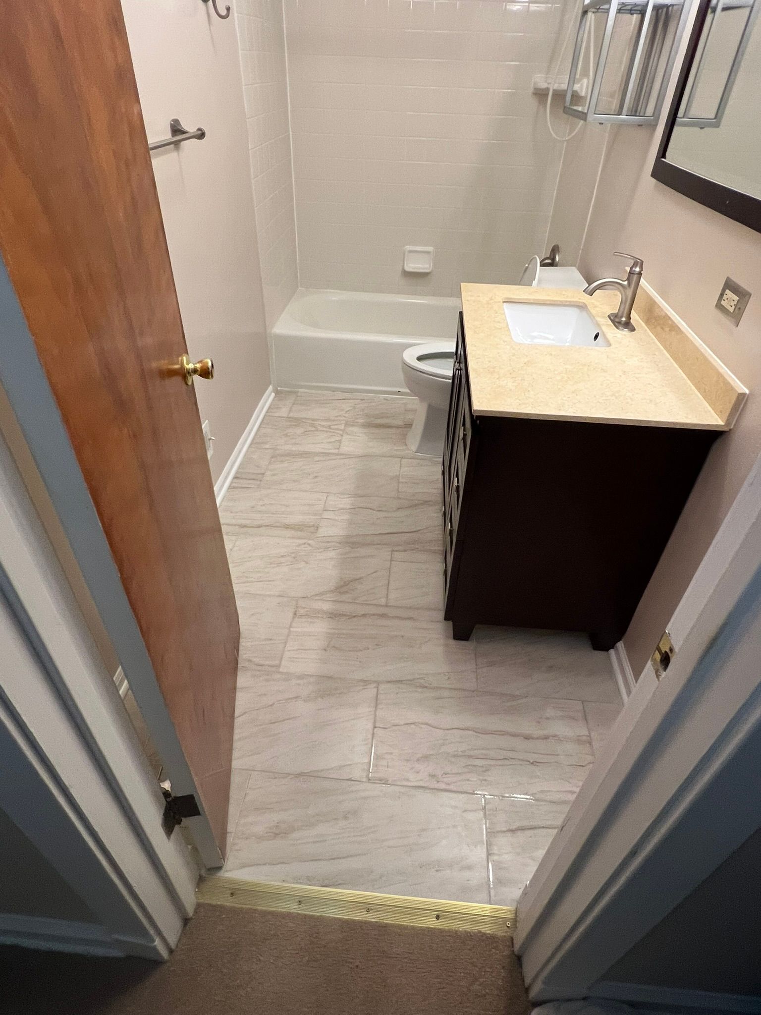 Bathroom with brown vanity, beige walls, tiled floor, and a shower.