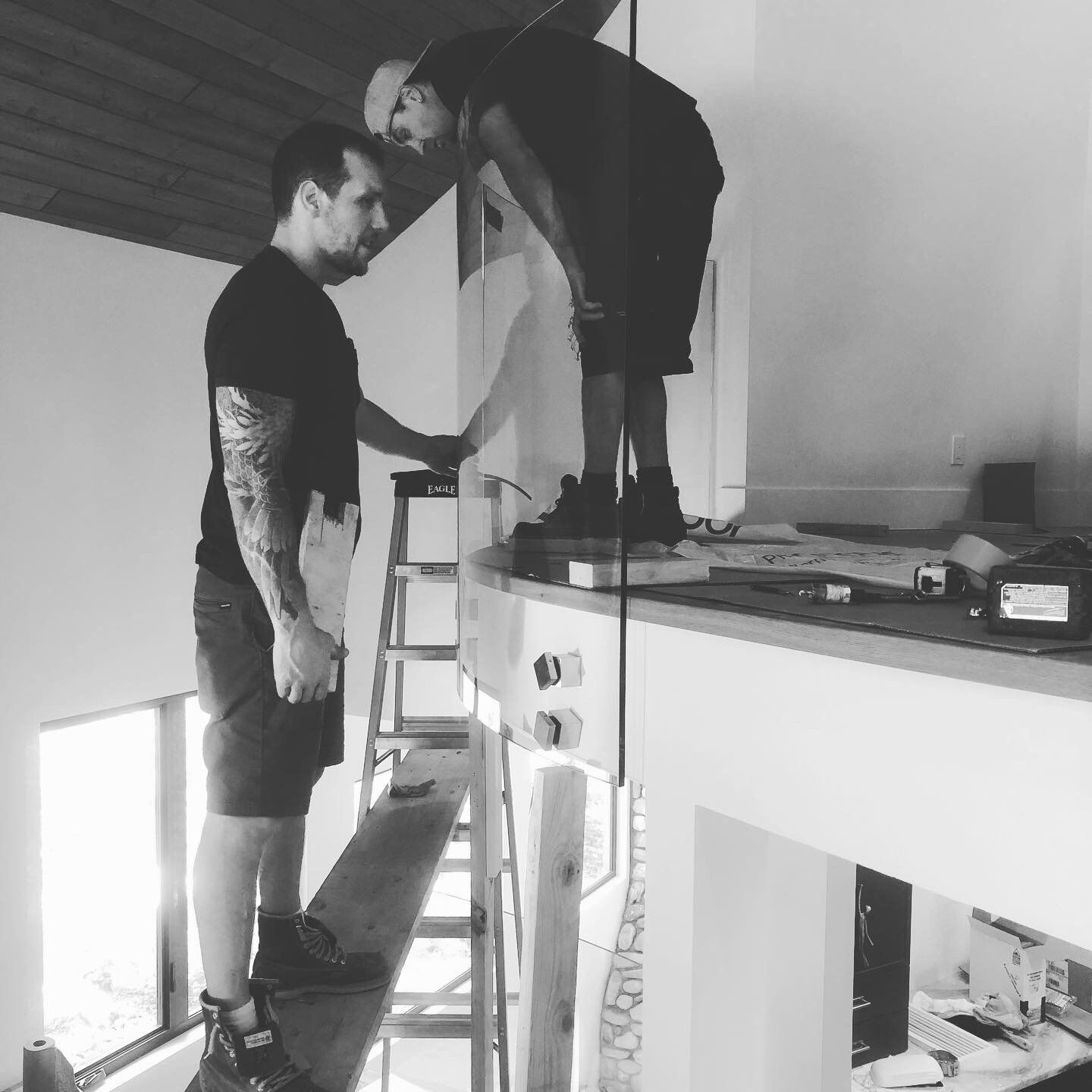 A black and white photo of two men working on a wall