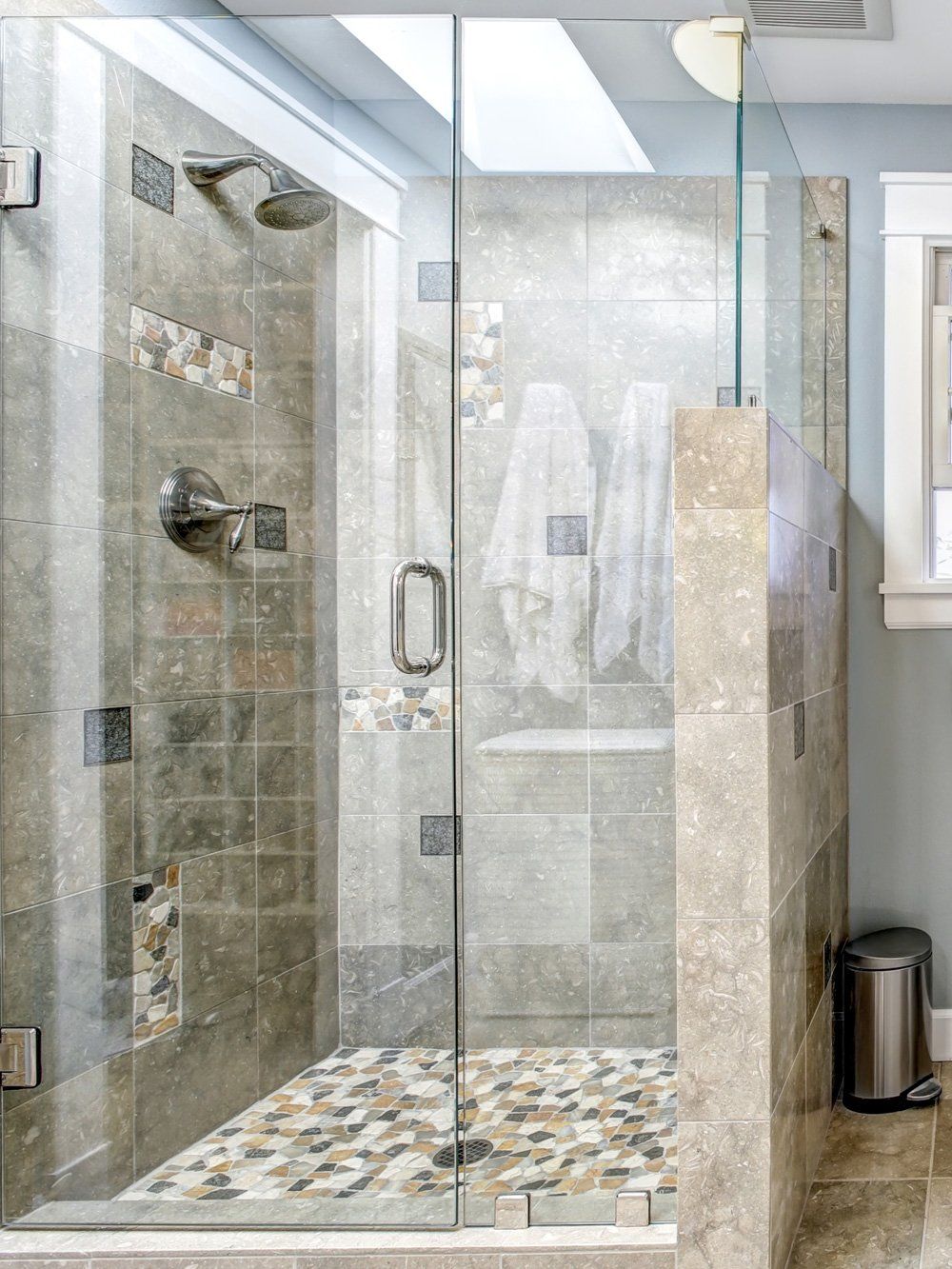 A bathroom with a walk in shower with a glass door.