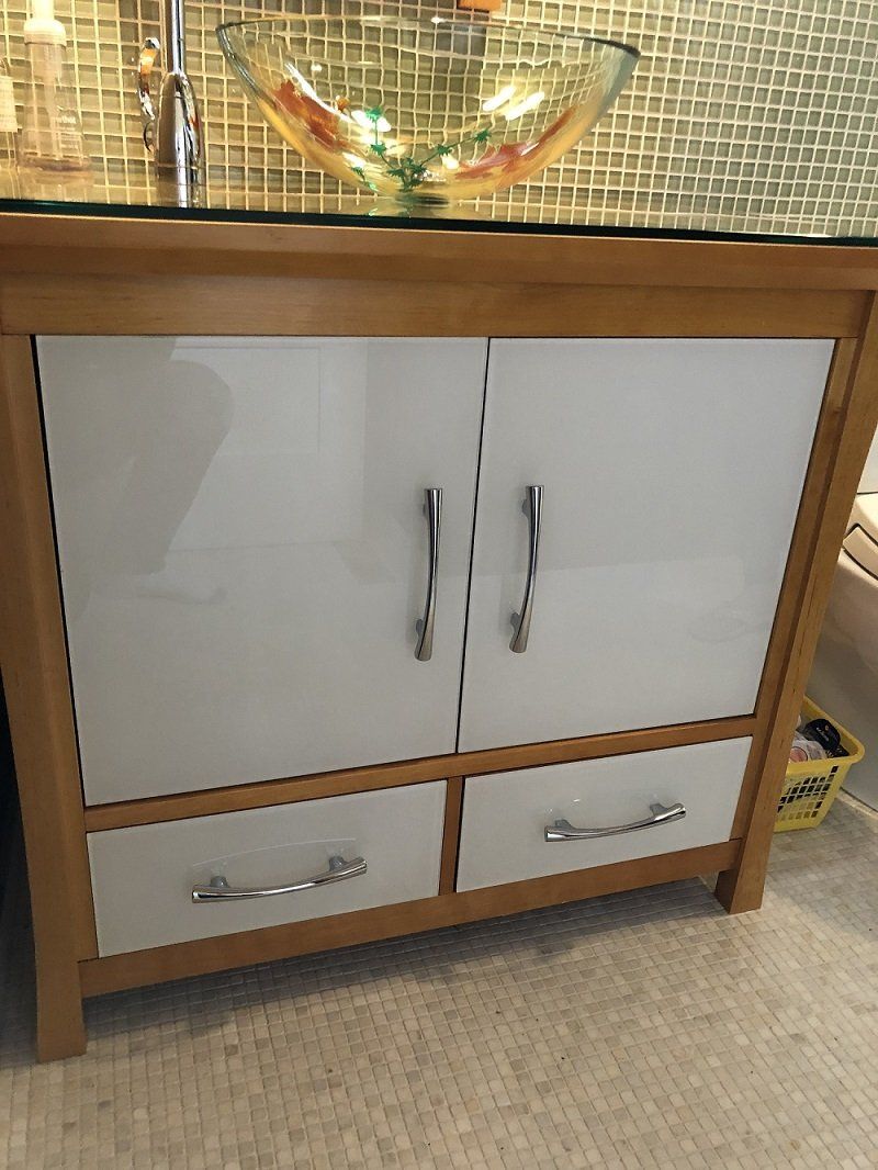 A bathroom vanity with a sink and a glass top.