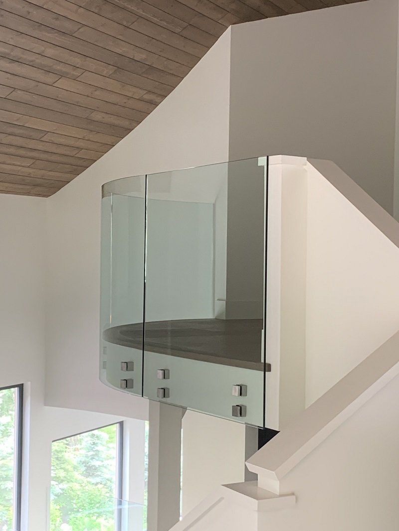 A staircase with a glass railing and a wooden ceiling