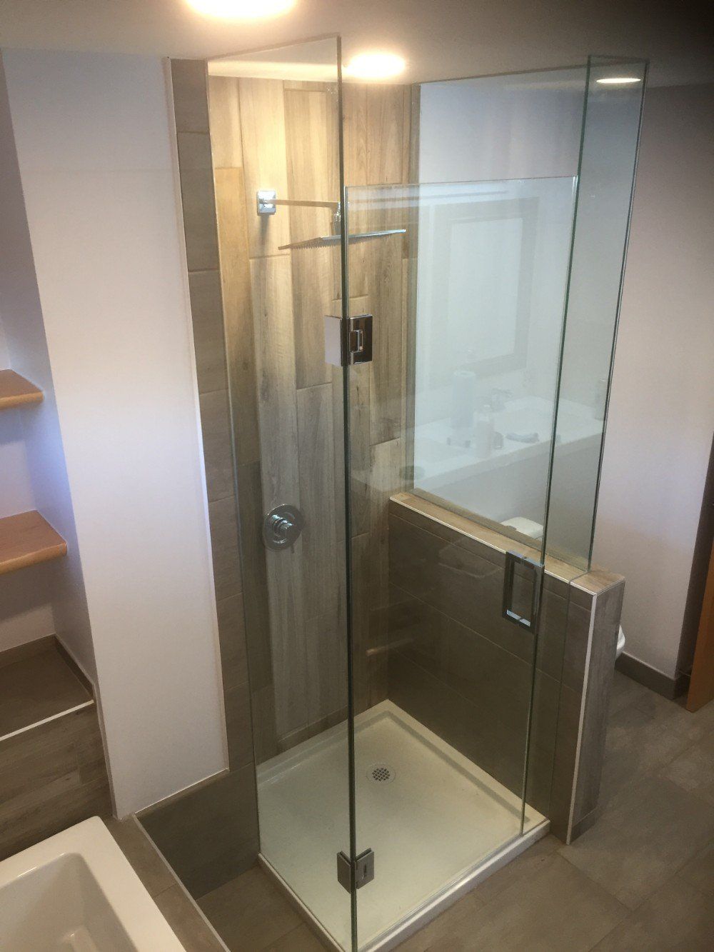 A bathroom with a walk in shower with a glass door