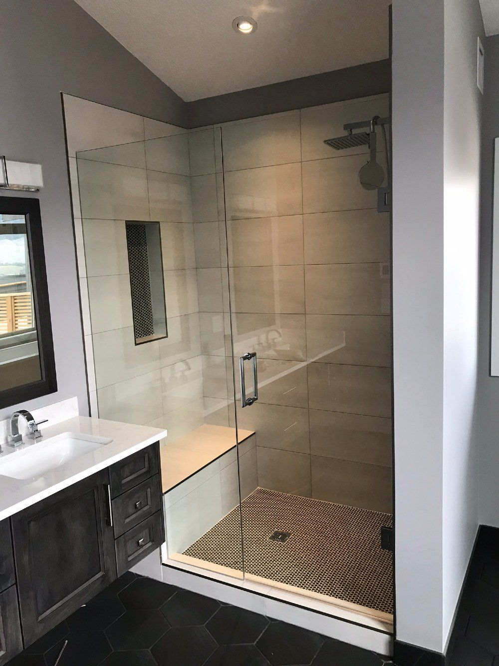 A bathroom with a walk in shower , sink and mirror.