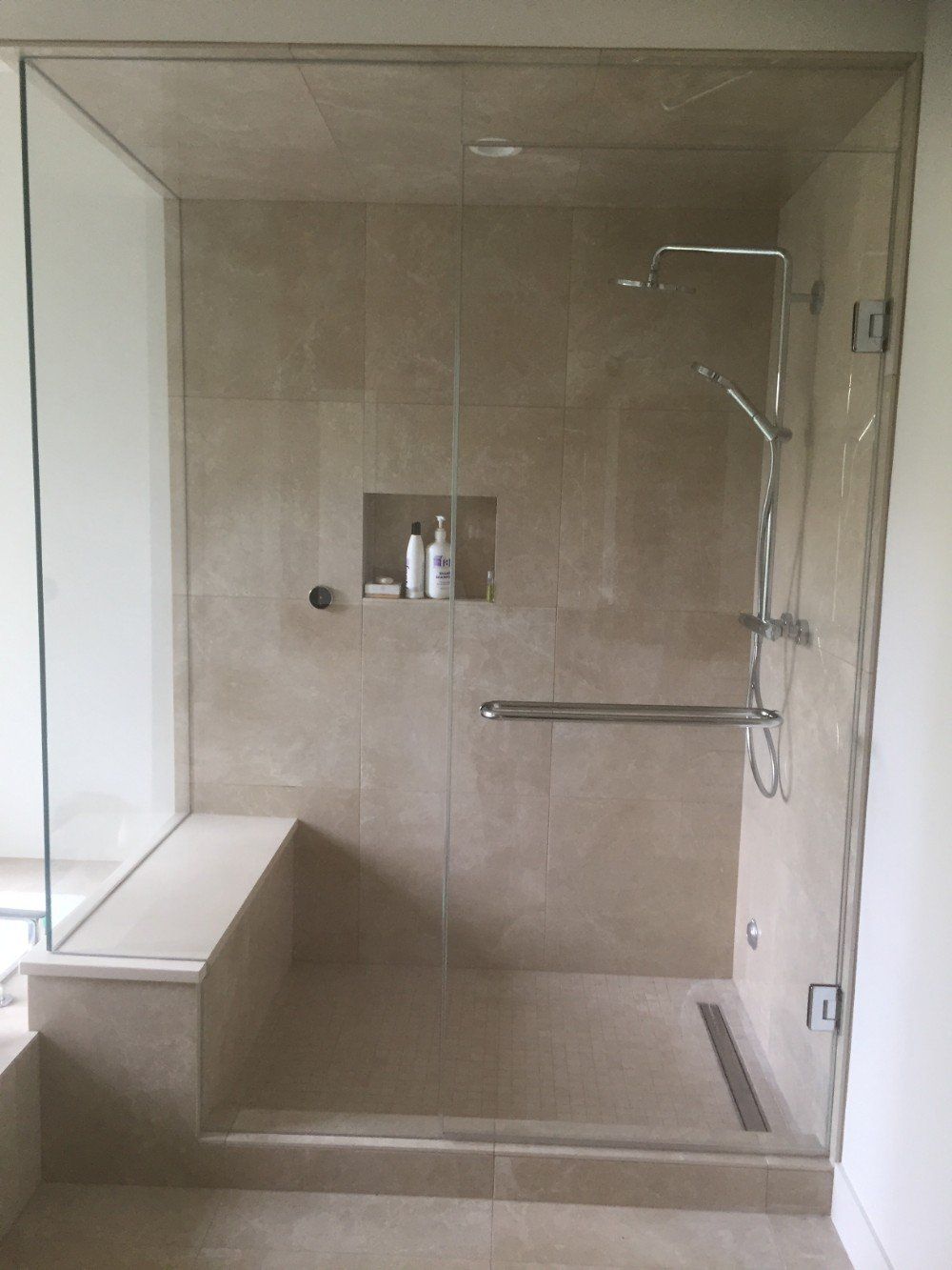 A bathroom with a walk in shower with a glass door