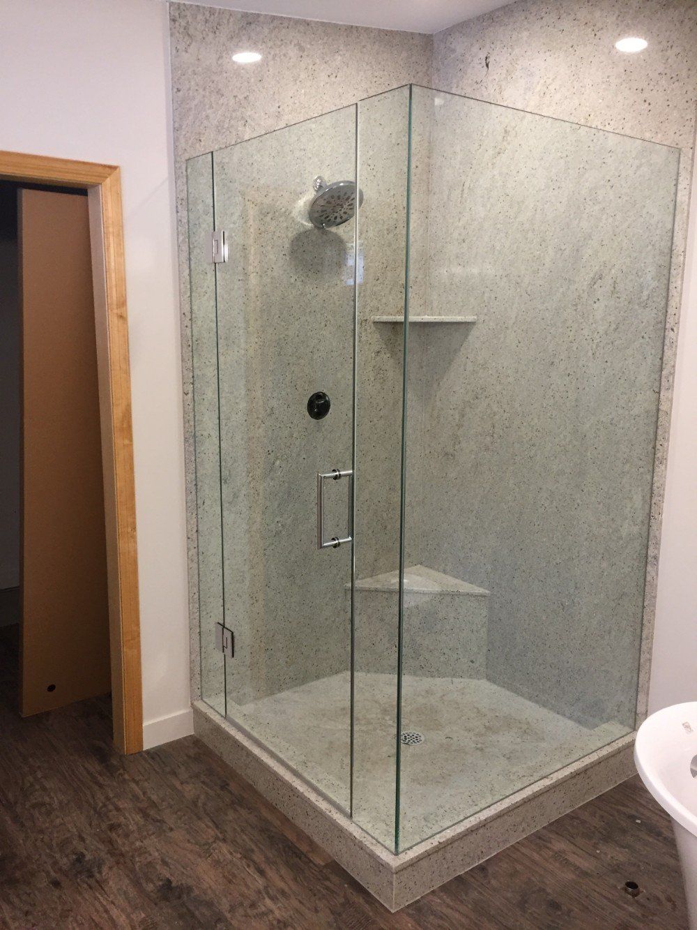 A bathroom with a walk in shower with a glass door.