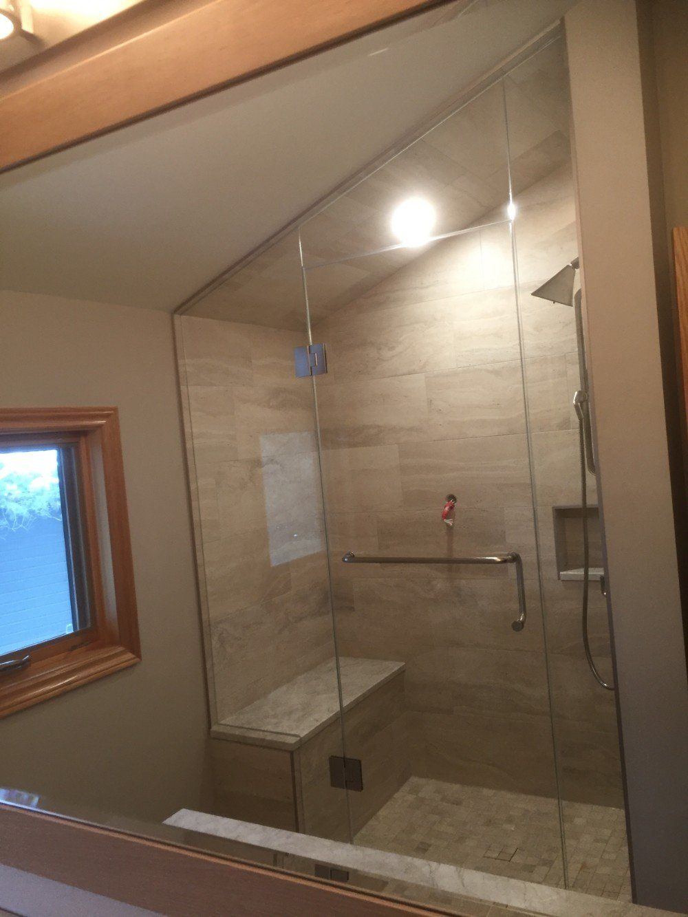 A bathroom with a walk in shower and a window