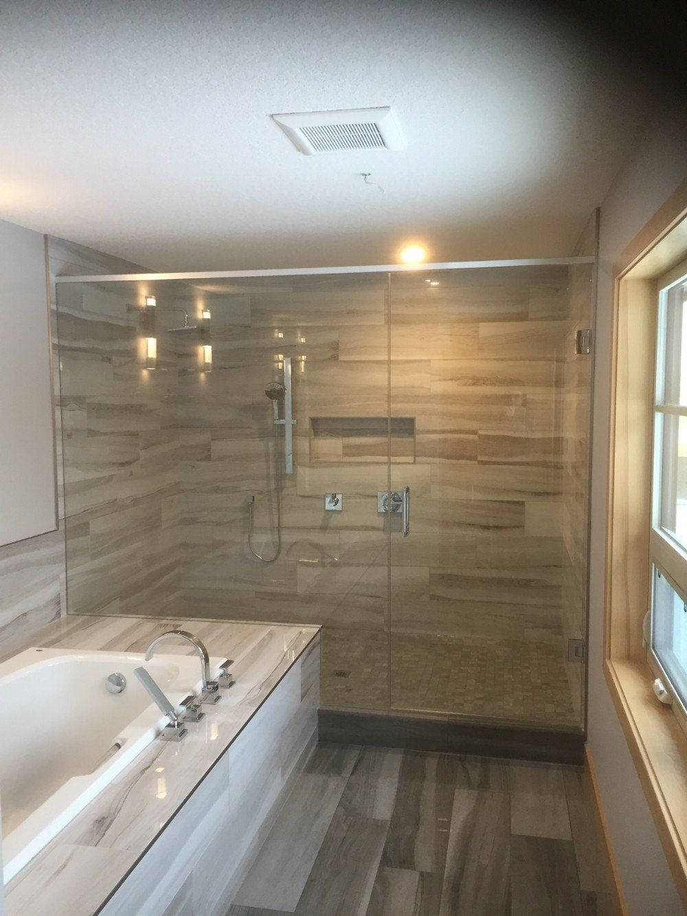 A bathroom with a tub and a shower with a glass door
