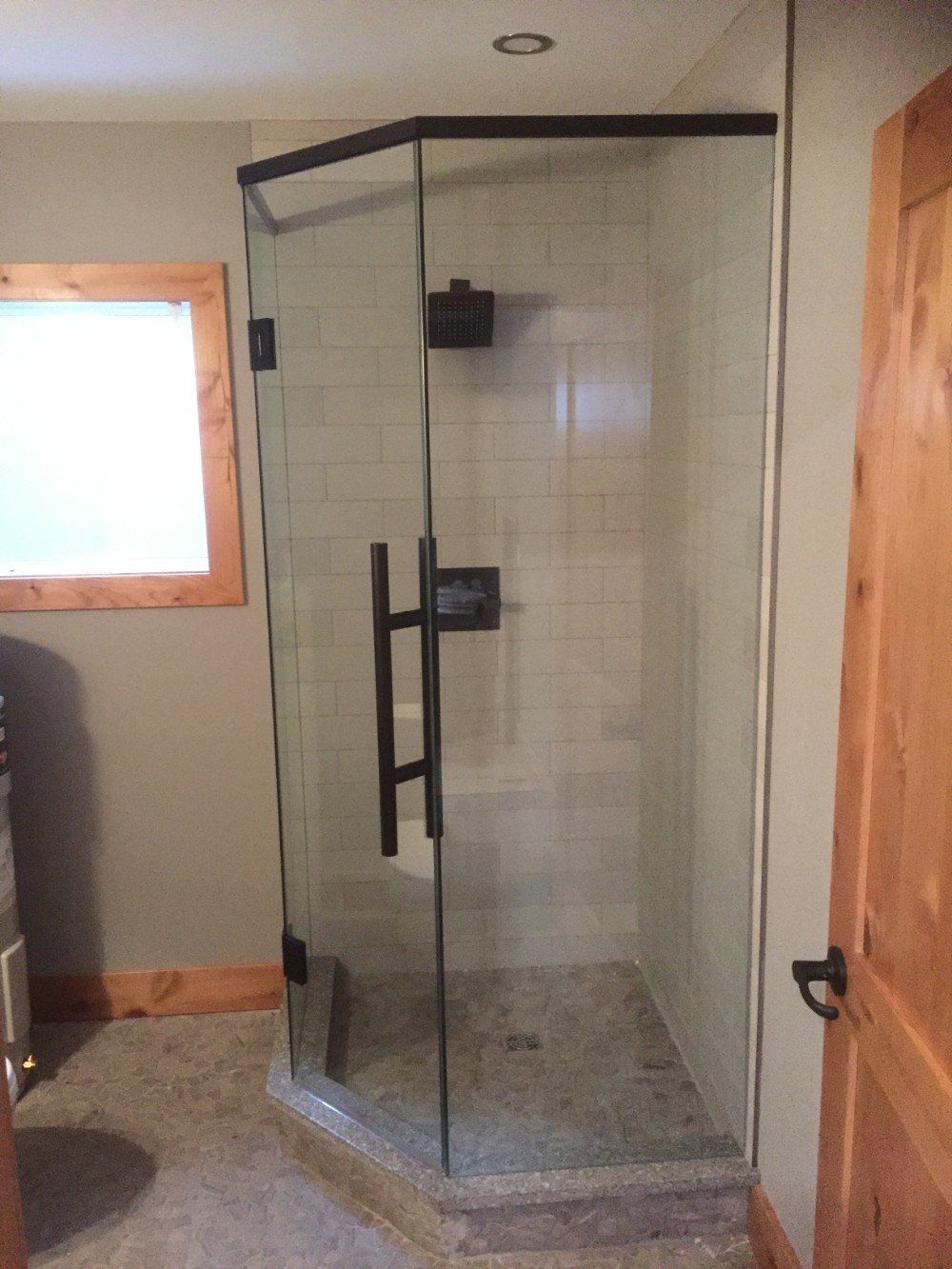 A bathroom with a shower stall and a window