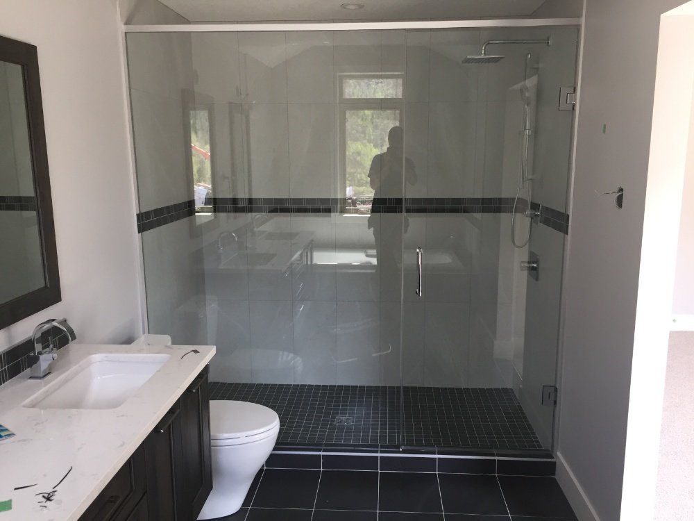 A bathroom with a toilet , sink and walk in shower.