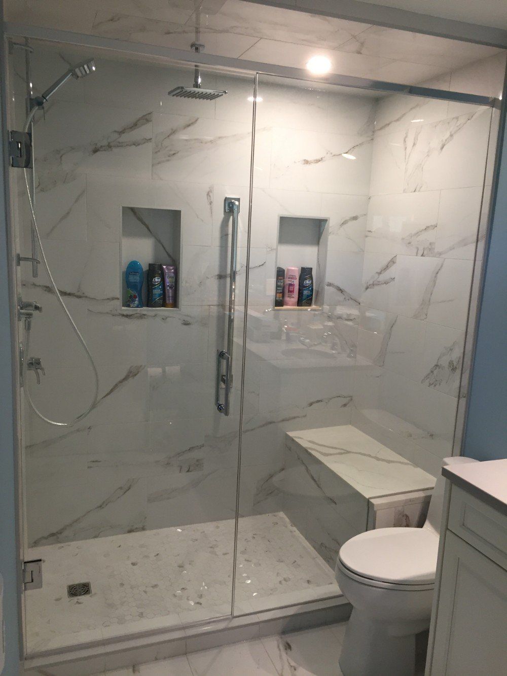 A bathroom with a walk in shower , toilet and sink.