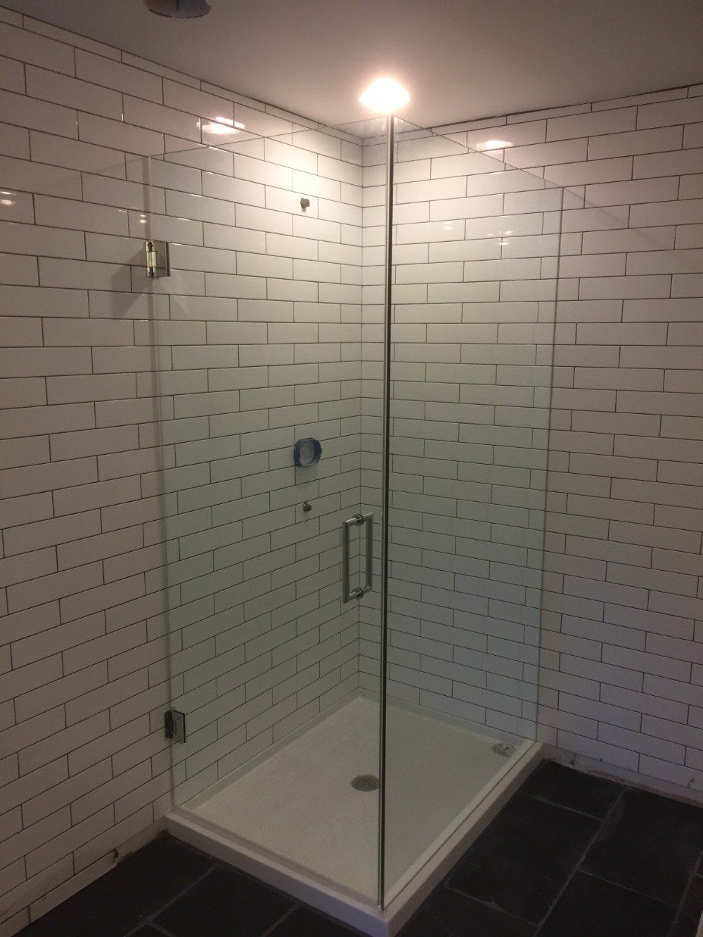A bathroom with white brick walls and a walk in shower