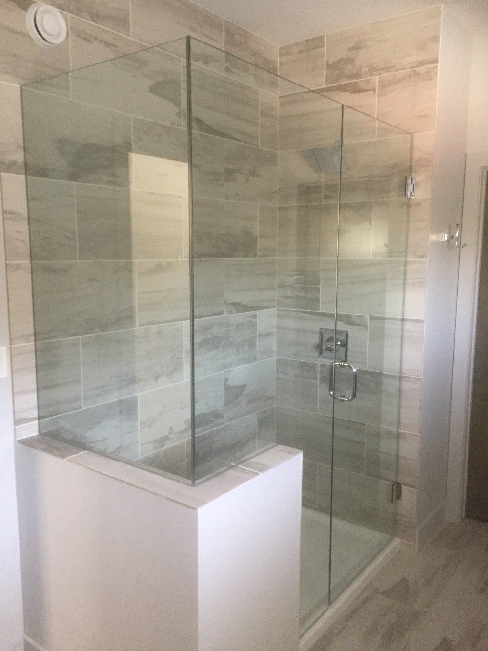 A bathroom with a walk in shower with a glass door.