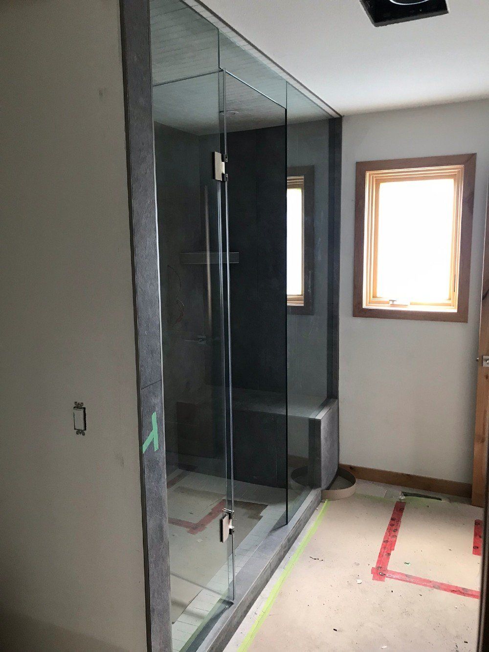 A bathroom with a glass shower door and a window.