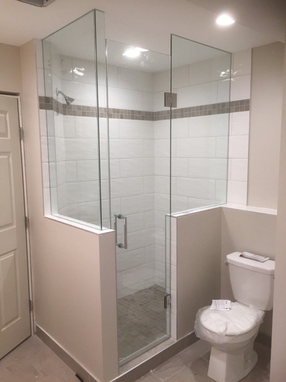 A bathroom with a toilet and a shower with a glass door.