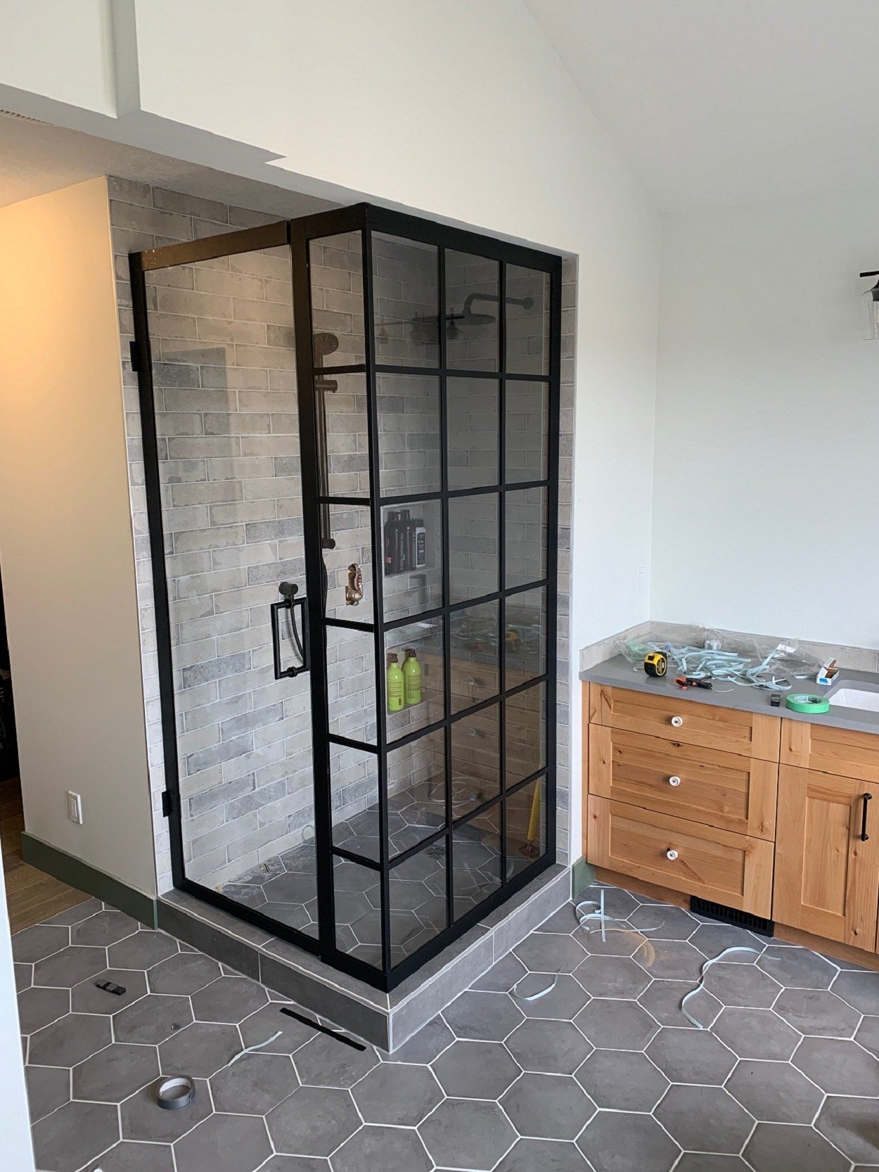 A bathroom with a walk in shower with a black frame.