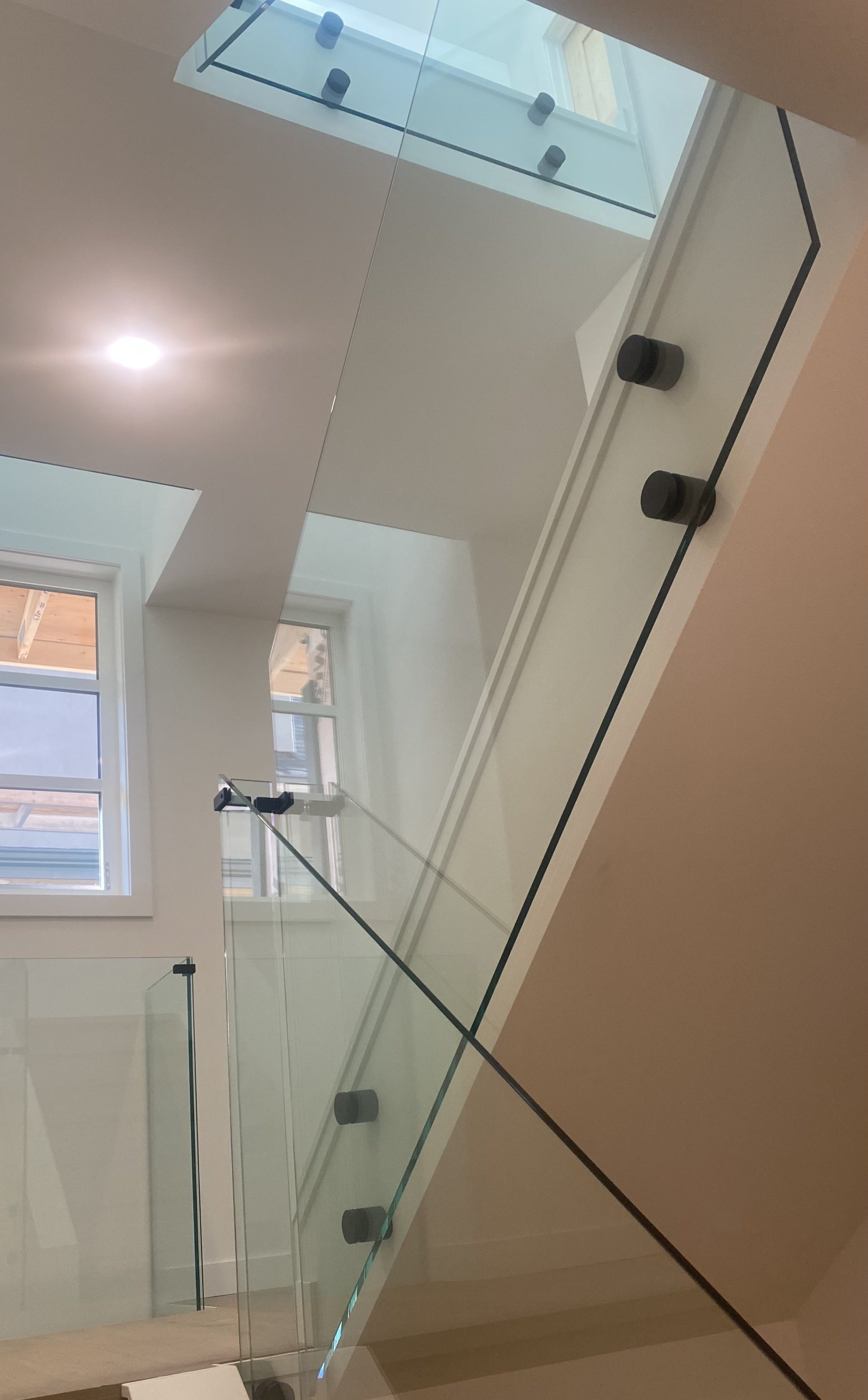 A staircase with a glass railing and a window.