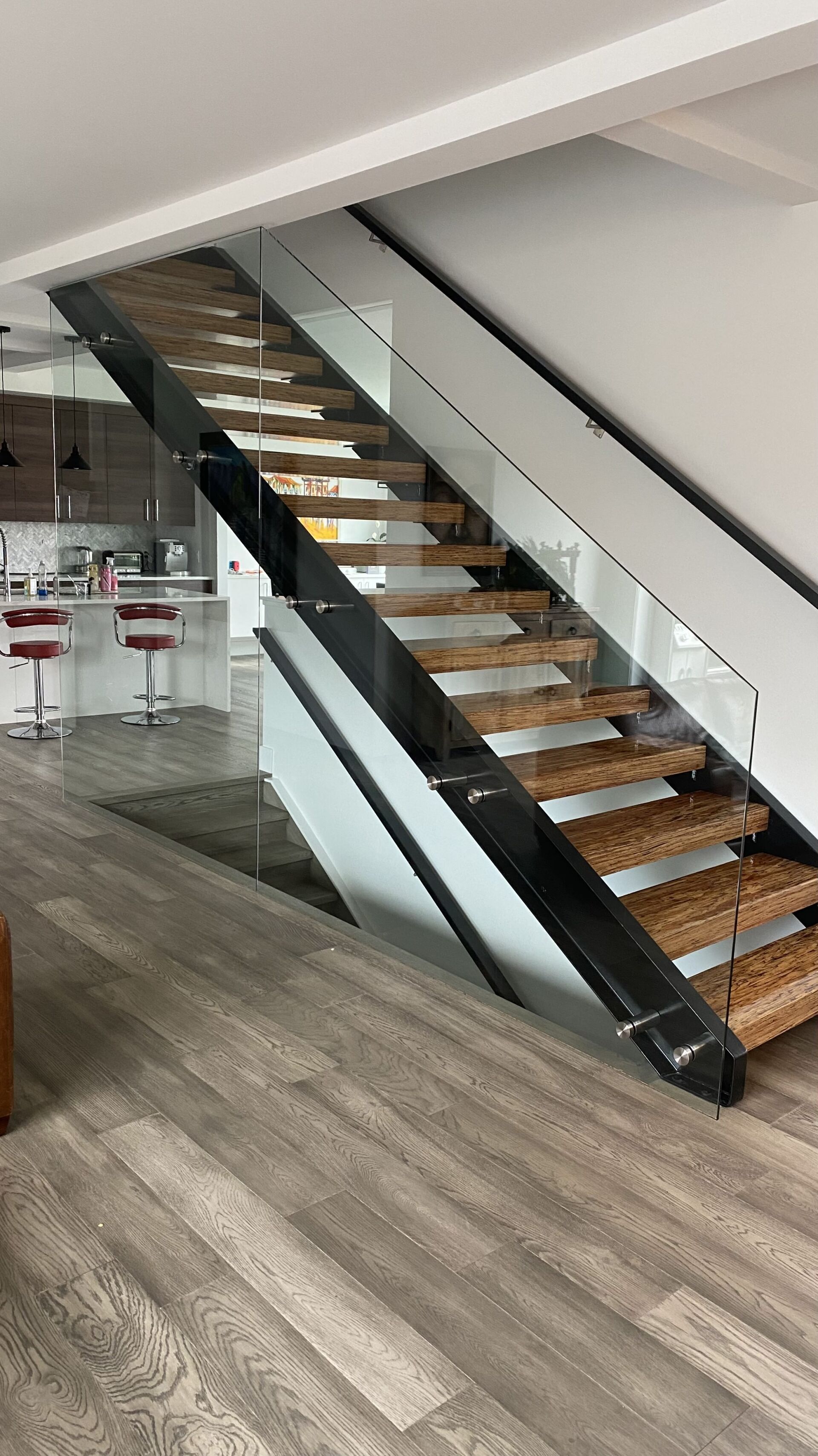 A modern staircase with wooden steps and a glass railing in a living room.