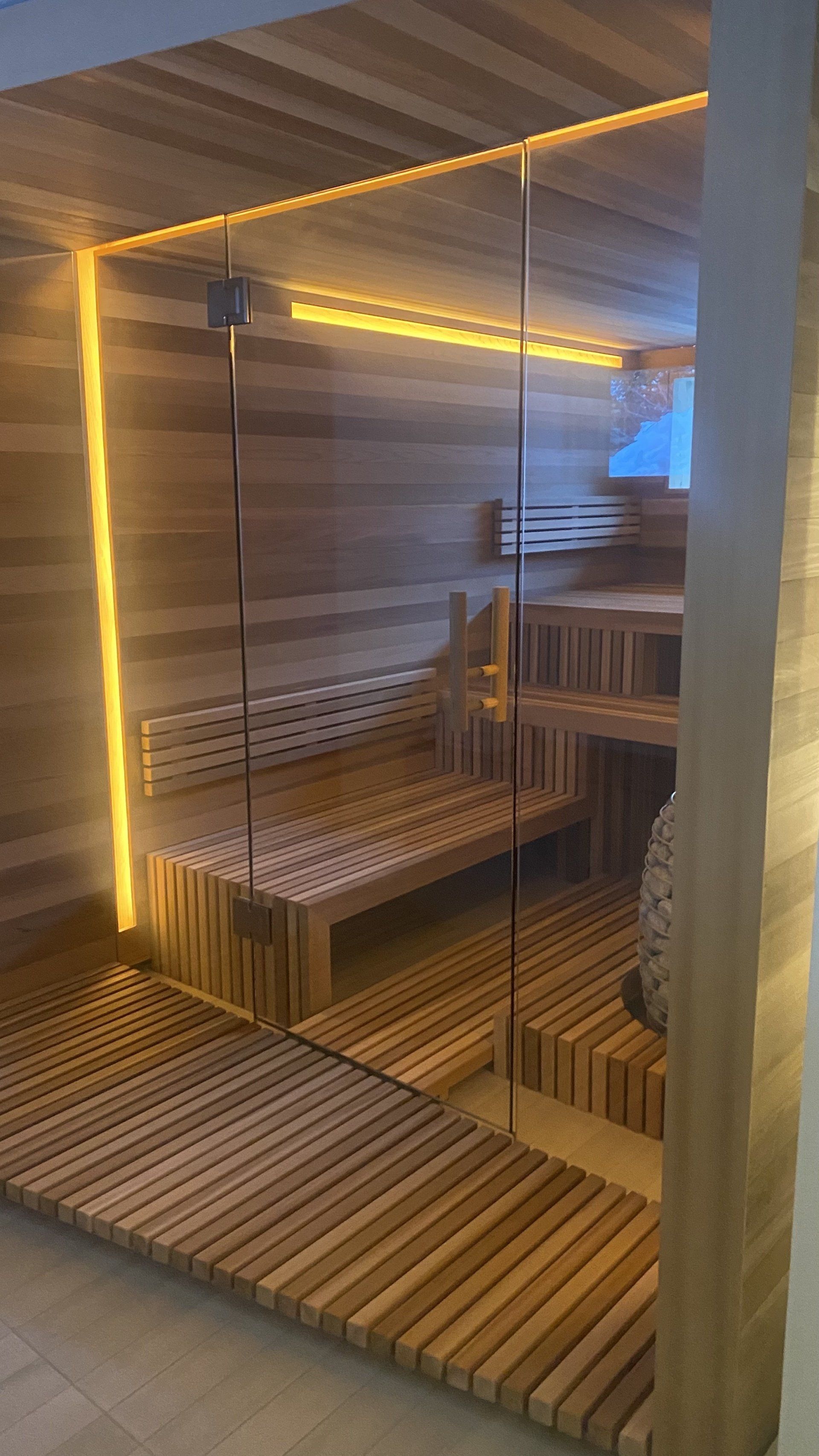 A wooden sauna with a glass door and a wooden floor.