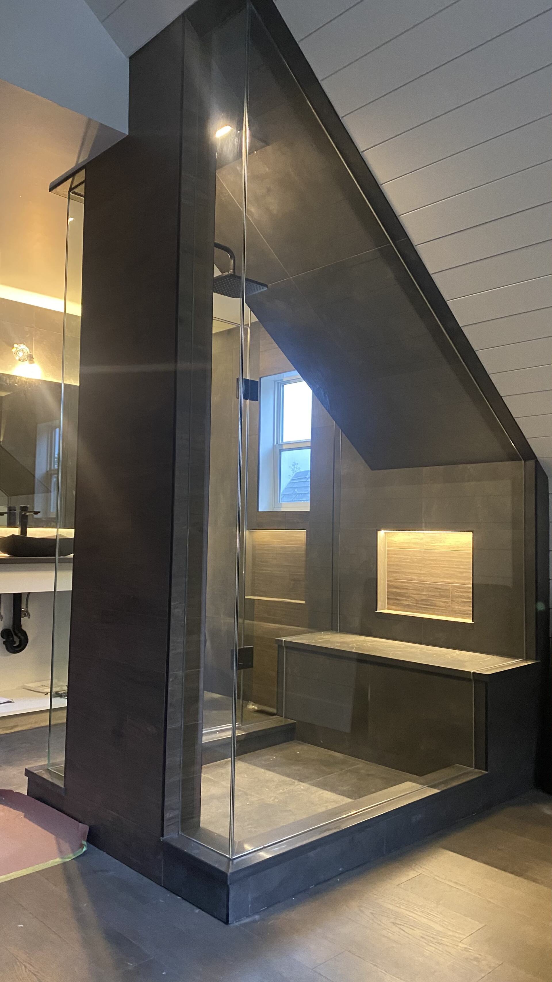 A bathroom with a shower and a bathtub under a staircase.