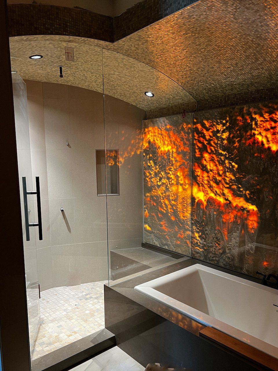 A bathroom with a bathtub and a shower with a fire wall