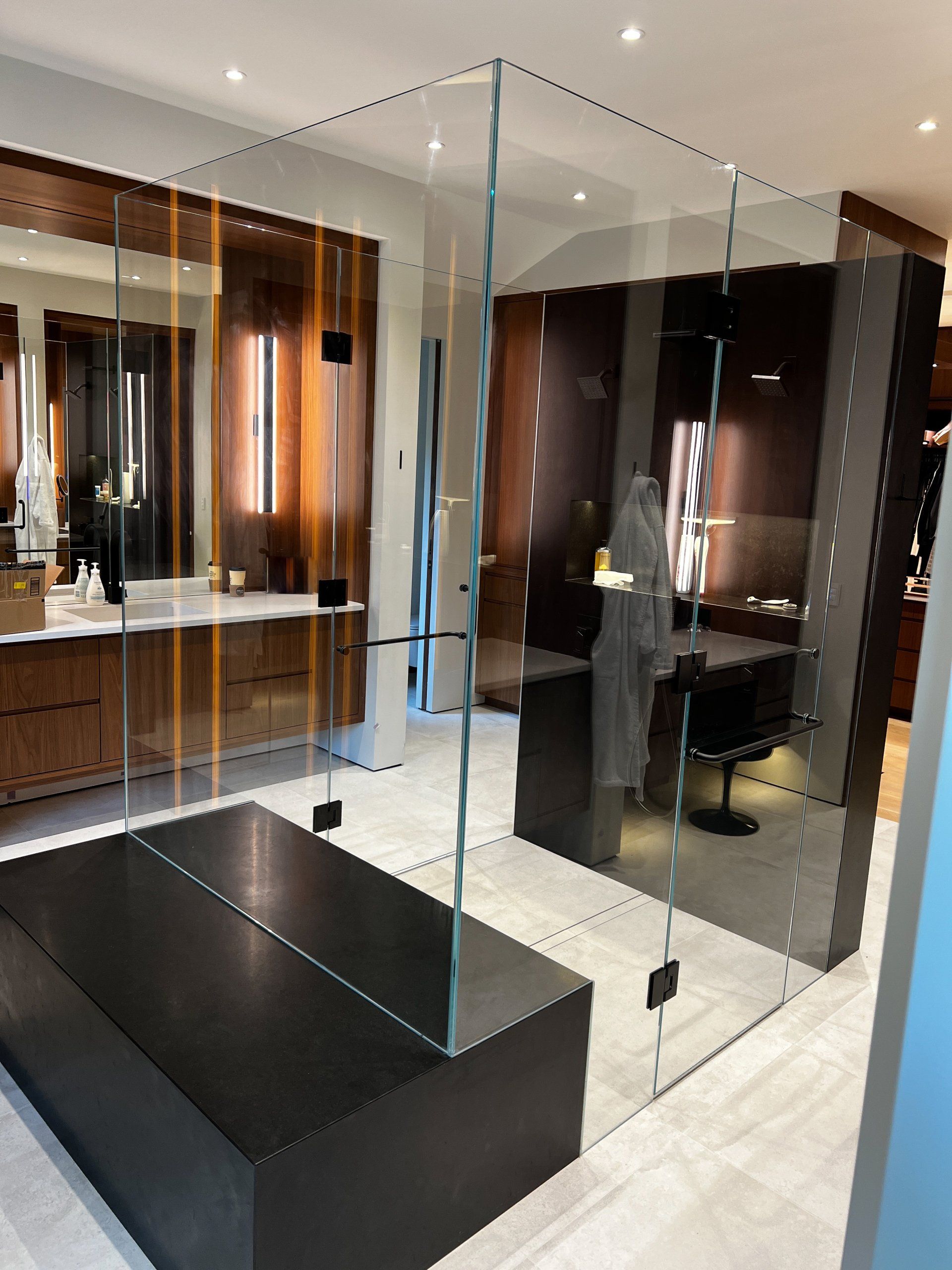 A bathroom with a glass wall and a black bench