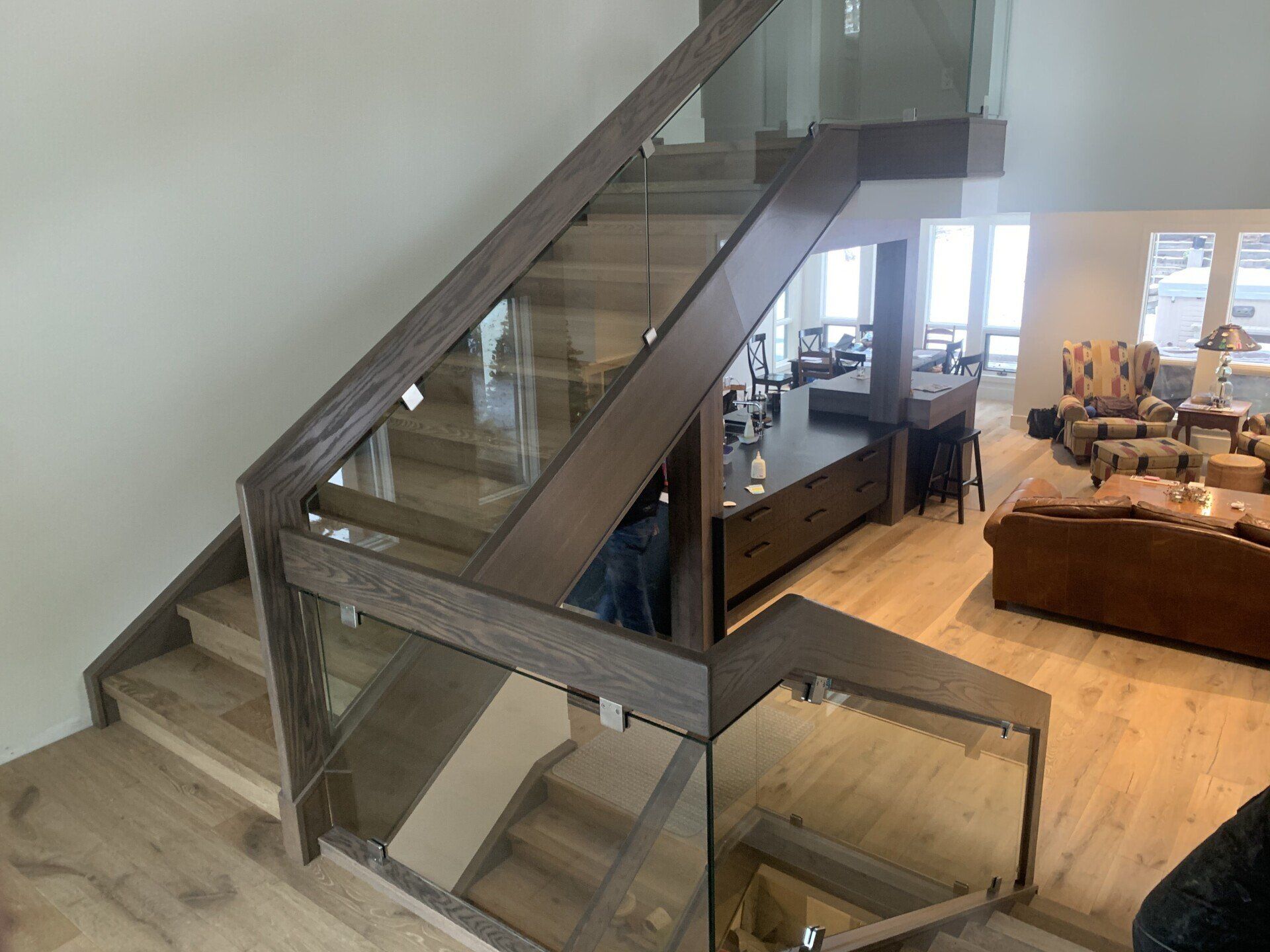 A wooden staircase with a glass railing in a living room.
