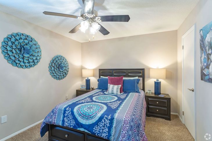 Bedroom with bed, nightstands, lamps, blue and pink decor, and ceiling fan.