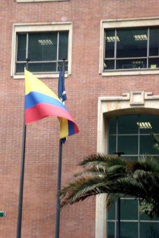 Dos banderas ondean frente a un edificio de ladrillos