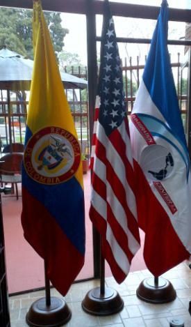 Tres banderas se exhiben frente a una ventana, incluida una de Colombia.